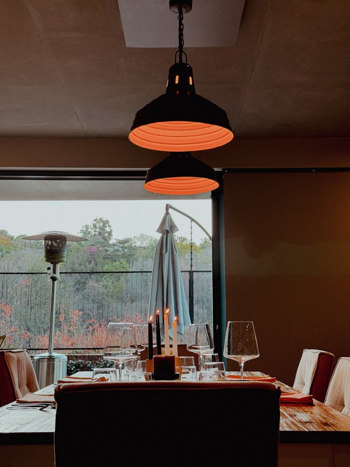 A beautifully set dining table by a window with warm lighting and an outdoor view, perfect for fine dining.