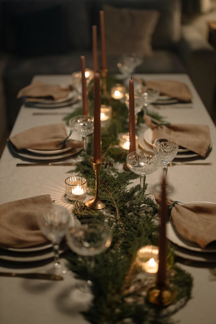 Beautifully set dining table with candles and greenery for a cozy holiday dinner.